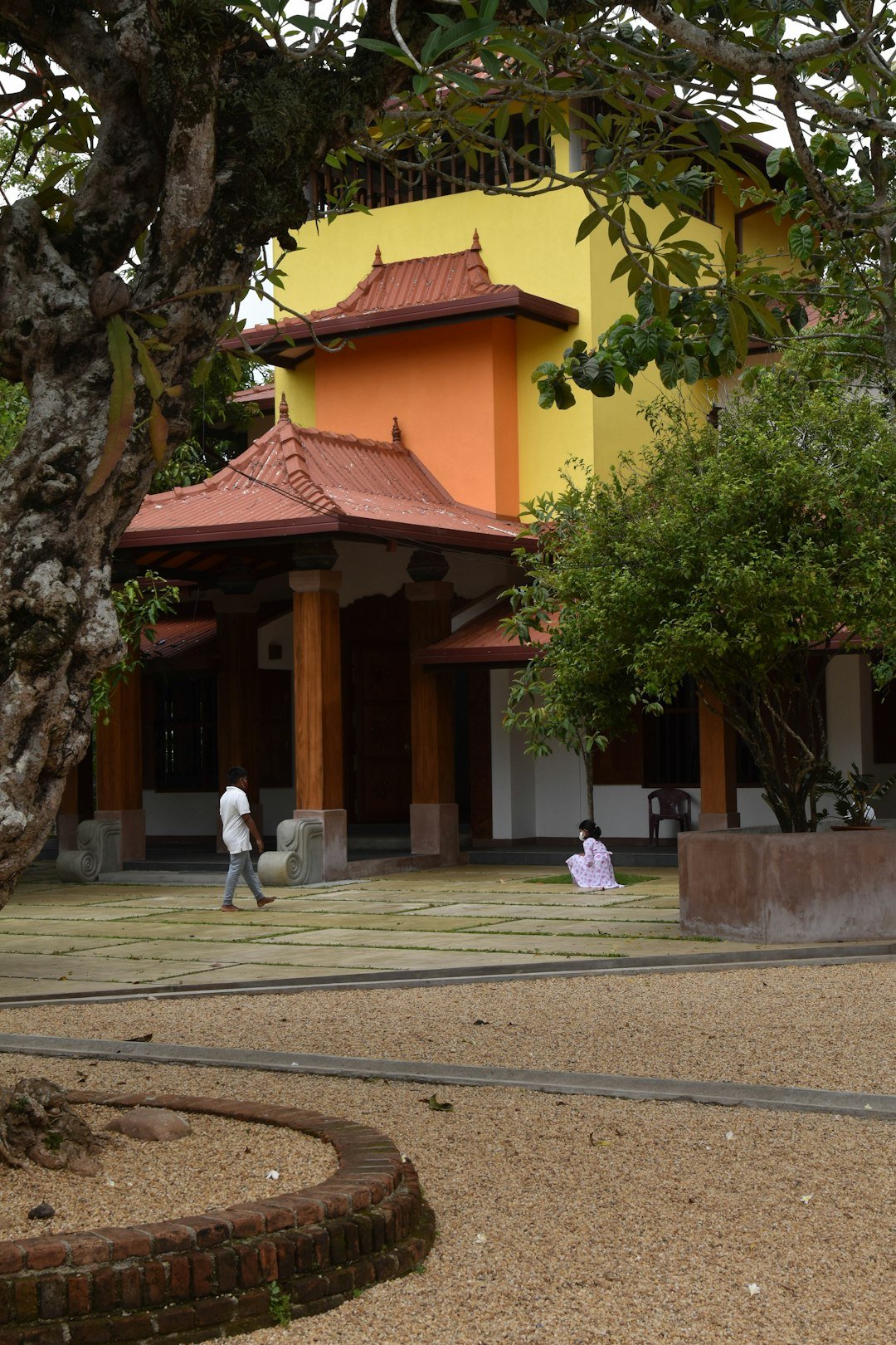a-couple-of-people-sitting-on-a-bench-in-front-of-a-building-nzrnfnkrnpw